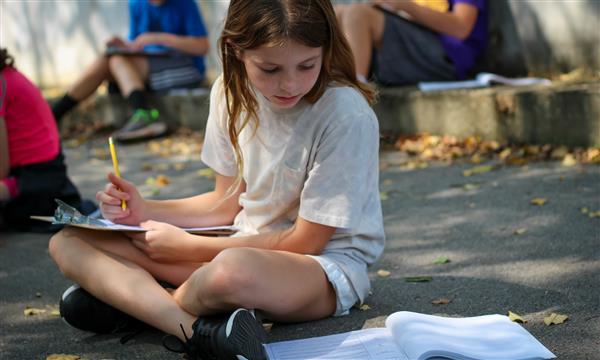 student writes on clipboard